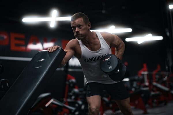 Man performing dumbbell row in modern gym, showcasing strength and dedication.