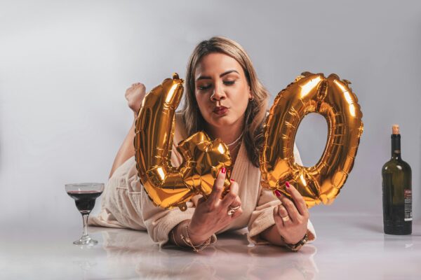 Woman celebrating her 40th birthday with golden balloons and a glass of wine.