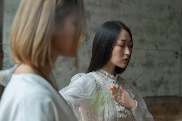 Two women practicing meditation indoors, conveying tranquility and focus in a serene setting.